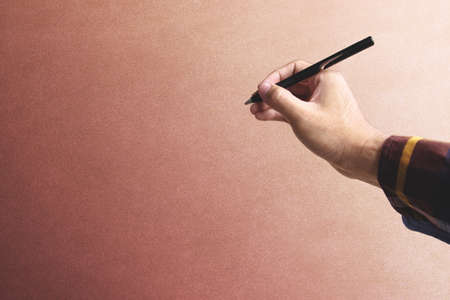 Hipster hand holding pen over old vintage wall background with copy spaceの写真素材