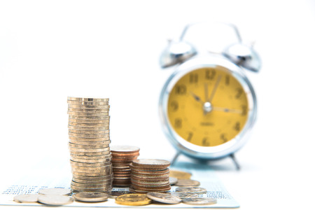 Stack of coins with vintage clock on white background for mocup display planning Money Financial and business Accounting Conceptの写真素材