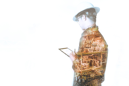 Double exposure of Engineer or Technician man with safety helmet operated platform or plant by using tablet with offshore oil and gas platform background for oil and gas business concept.の写真素材