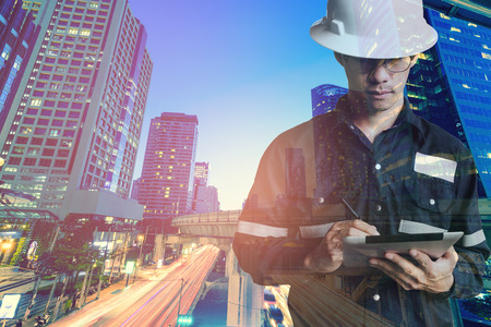 Double exposure of Engineer or Architecture man in working shirt and safety helmet working with...