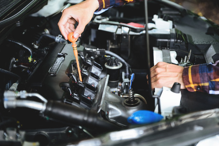 Close up hands checking lube oil level of car engine from deep-stick for service and maintenance...