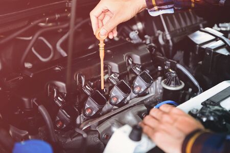 Close up hands checking lube oil level of car engine from deep-stick for service and maintenance concept vintage tone.の写真素材