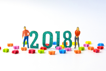 2018 New year concept man and woman miniature figures standing on 2 0 1 8 number with colorful stars on white background.の写真素材