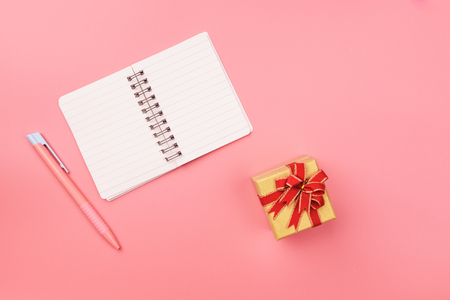 Blank notebook with pen and gift box on top of pink pastel desk. Top view with copy space, flat lay.の写真素材