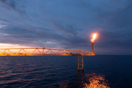 Fire on flare stack at oil and gas central processing platform while burning toxic and release over pressure from process for industry business concept.の写真素材