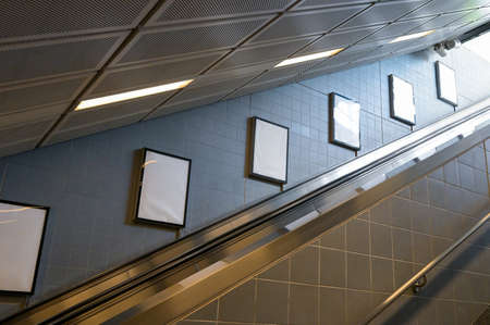 Blank poster or billboard in public place. Billboard mockup near to escalator in an mall, shopping...