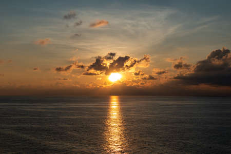 Golden sunrise or sunset on the sea, over which hung a big clouds and the sky is beautiful quiet atmosphere feeling lonely.の写真素材