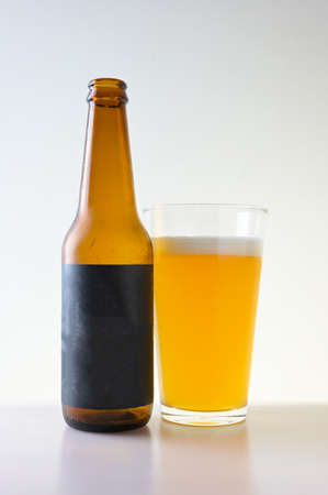 Glass and bottle of beer on white background with black blank label.の写真素材