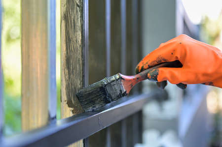 Worker painting steel with paint brush and orange gloves selective focus on hand.の写真素材