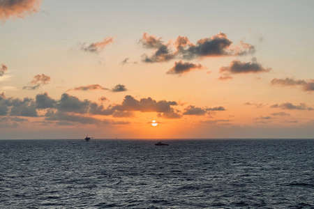 Beautiful sunset in the Sea with offshore well head platform and supply boat in dramatic tone.の写真素材