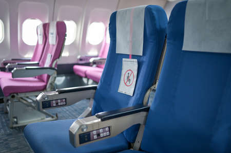Empty passenger airplane seats in the cabin blue and pink with social distancing to prevent infection during pandemic.の写真素材