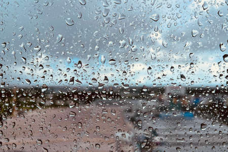 Rain drops on the clear glass. Beautiful raining sky with city background.の写真素材