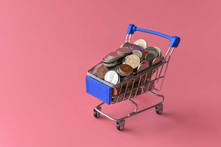 Many coins in the blue shopping cart Isolated on pink background and copy space, saving and investment concept.の写真素材