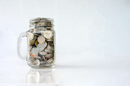 coins in classic glass jar on white background saving and investment concept.の写真素材