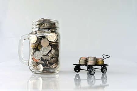 coins in glass jar and coins in cart on white background saving and investment concept.の写真素材