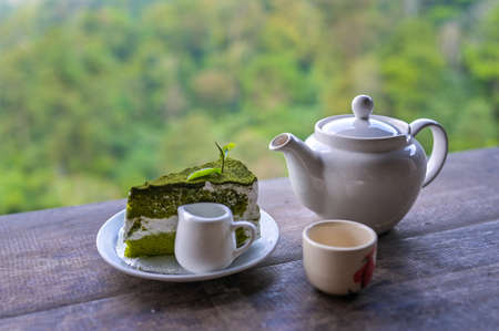 Tea set, Cups and teapot of green tea on wooden board with mountain and forest background.の写真素材