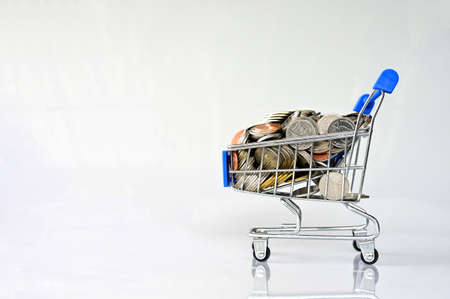 Many coins in the blue shopping cart Isolated on white background and copy space, saving and investment concept.の写真素材
