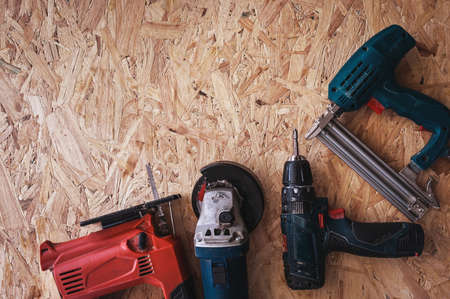 Group of electric hand tools jigsaw, grinder, drill, nail gun and white safety helmet on wooden background.の写真素材