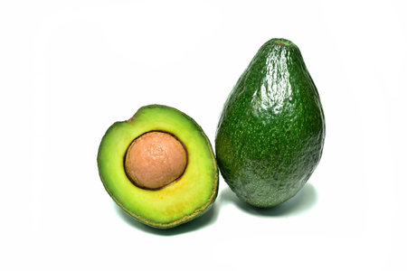 Avocado. Fresh green fruit high in vitamins. Cut it in half to reveal the flesh and seeds inside.  placed on a white backgroundの写真素材