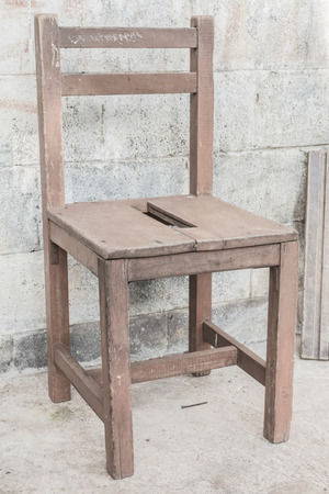 old chair is standing in front of a house with a stony wallの写真素材