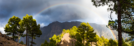 rainbow in front of mountains during stormy weatherの写真素材