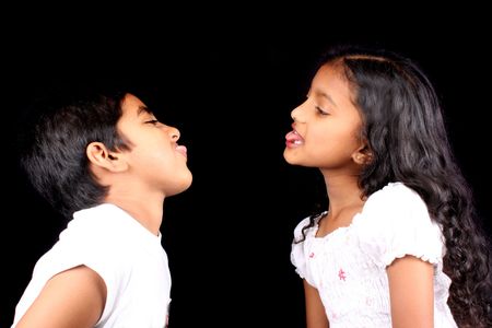 A portrait of an Indian brother and sister teasing each other, isolated on a black studio background.の写真素材