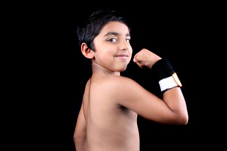 A little Indian boy showing his body after exercising, on black studio background.の写真素材