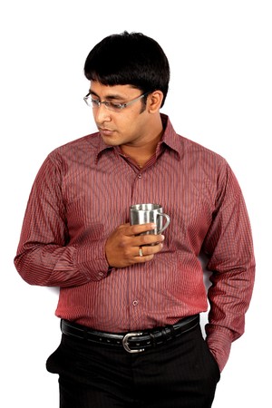 A tensed Indian guy/executive holding a coffee cup, leaning against a white wall.の写真素材
