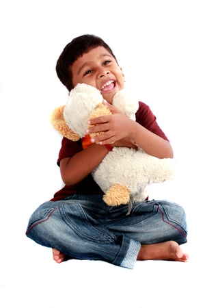 A cute Indian boy with a soft toy dog, on white studio background.の写真素材