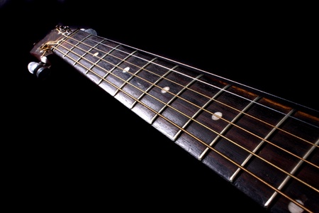 The fretboard of an acoustic guitar, on black background.の写真素材