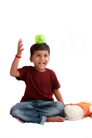 A playful Indian boy balancing a ball on his head, on white studio background.の写真素材