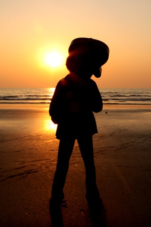 A silhouette of a guitarist looking at the setting sun on a beach.の写真素材