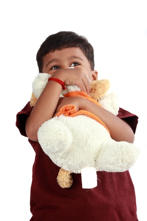 An Indian boy hugging his soft teddy bear, on white studio background.の写真素材