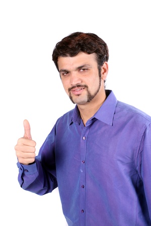 A young Indian guy wishing the best with a thumbs up sign, on white studio background.の写真素材