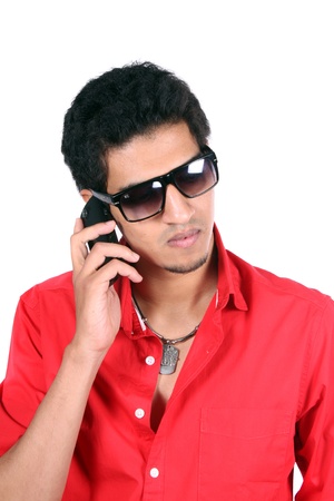 A young Indian guy talking on the mobile phone / cellphone, on white studio background.の写真素材