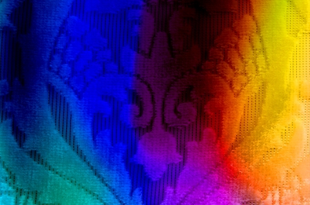 A background of a fabric with floral design, lit in colorful lights の写真素材