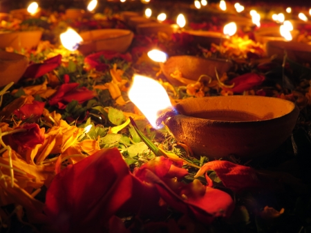 Traditional earthen oil lamps lit with flowers and petals for a holy ritual during Diwali festival...