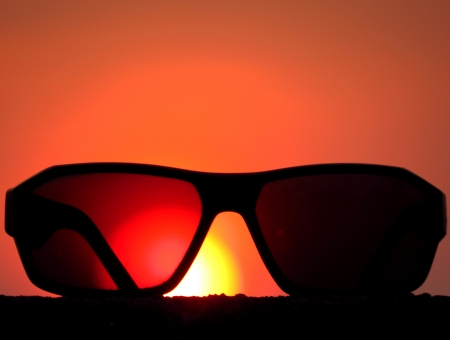 A metaphorical picture of sunglasses against the backdrop of the setting sun conceptualizing a holiday.                               の写真素材