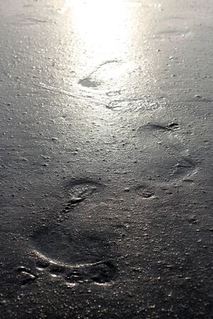 A metaphorical image showing the legacy of a human left behind in footprints imprinted in sandの写真素材