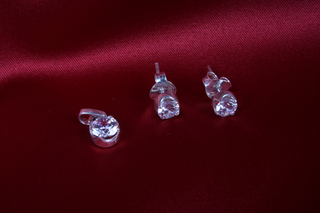 A beautiful diamond set casted in silver, on crimson studio background.の写真素材