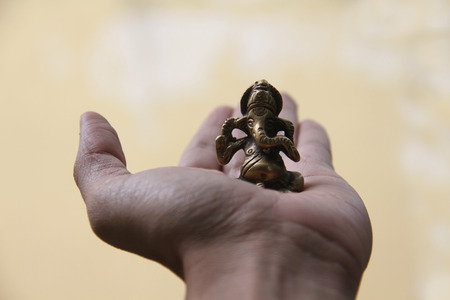 A beautiful antique brass idol of lord Ganesha held in the hand for luckの写真素材