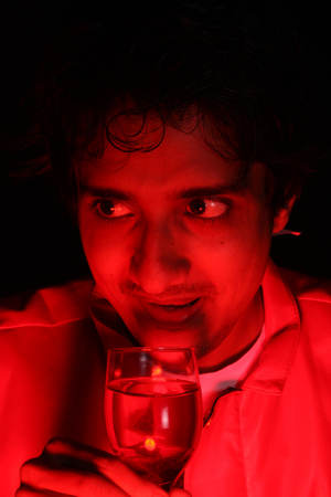 An Indian guy totally drunk on a wild party night, with a glass of wine in his hands.の写真素材