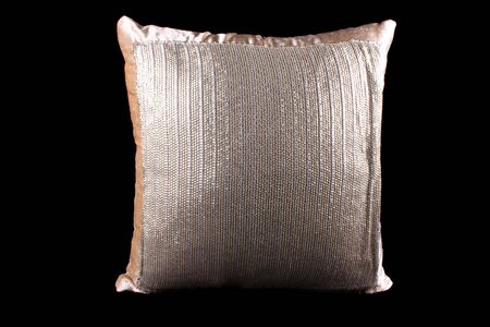A golden and silver colored shiny pillow with sequins on black studio background.の写真素材