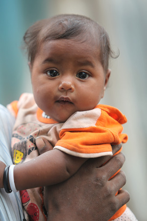 A innocent looking baby in the hands of her poor fatherのeditorial素材