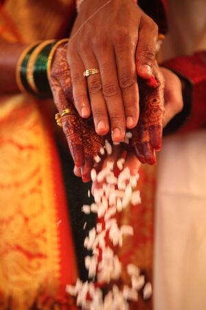 The hands of an Indian groom and bride performing a traditional wedding ritual.の写真素材