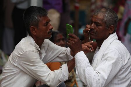 Pune, India  - âJuly 11, â2015:A streetside barber shaves a pilgrim during a huge pilgrimmage in Indiaのeditorial素材