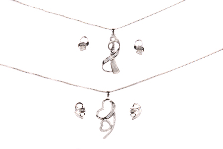 Two sets of silver jewelery beautifully designed with small gemstones, on white studio backgroundの写真素材