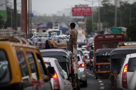 Traffic Jam with a milkman standing on his van during a cloudy rainy day in India.