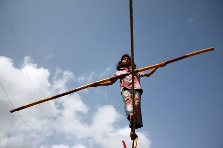 A street trapeze artist performs the balancing act on a tight rope in India.のeditorial素材