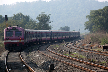 A small Indian train entering the wild forest area after departing from a station.の写真素材